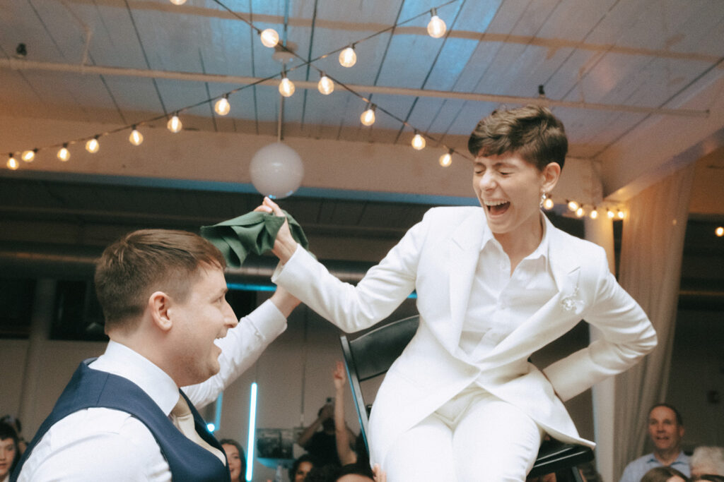 Couple laughing during the Hora at their wedding reception at Hope Events on Main - a nontraditional wedding venue in Rhode Island. Photo by Rhode Tripper Photography