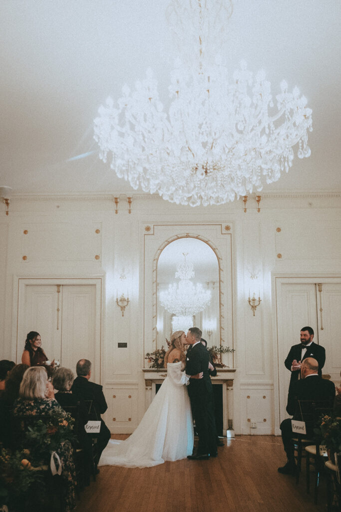 Couple kissing during their ceremony inside Tupper Manor - one of the best nontraditional wedding venues in the Boston area! Photo by Rhode Tripper Photography