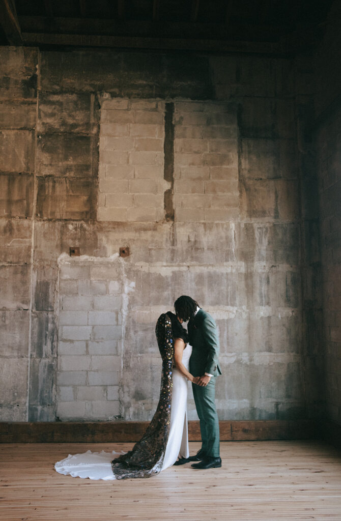 Couple kissing in their wedding attire at Olio Peabody -  one of the best nontraditional wedding venues in the Boston area! Photo by Rhode Tripper Photography