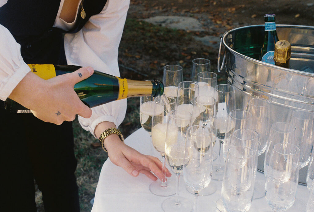 Castle Hill staff pours champagne for wedding guests to enjoy post-wedding ceremony. Photo by Rhode Tripper Photography