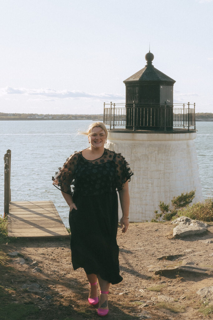 Wedding guest poses in front of the Castle Hill Lighthouse. Photo by Rhode Tripper Photography