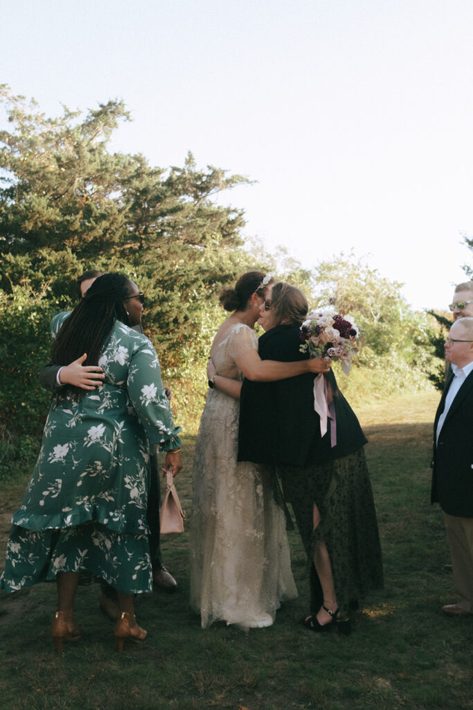 Bride and groom greet their guests after the ceremony has ended surrounded by greenery. Photo by Rhode Tripper Photography