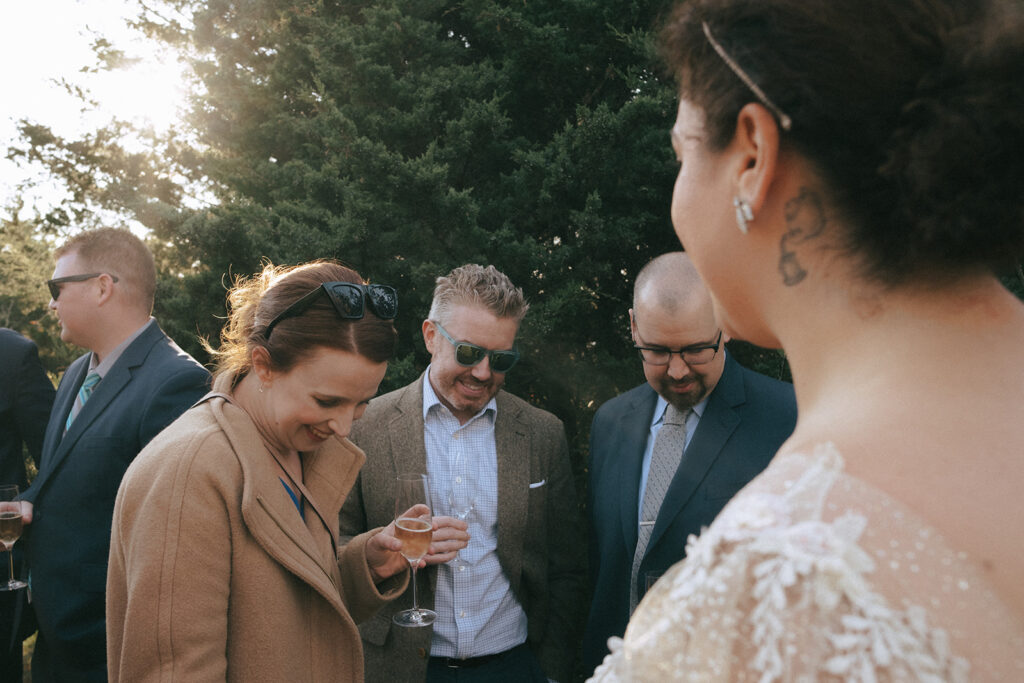 Wedding guests look to bride's dress and wedding ring. Photo by Rhode Tripper Photography