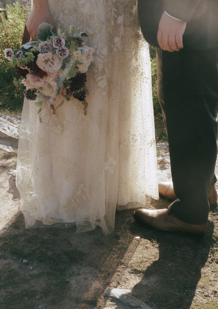 Close up of the light streaming between the legs of the bride and groom on the cliffs of the Castle Hill Lighthouse area.