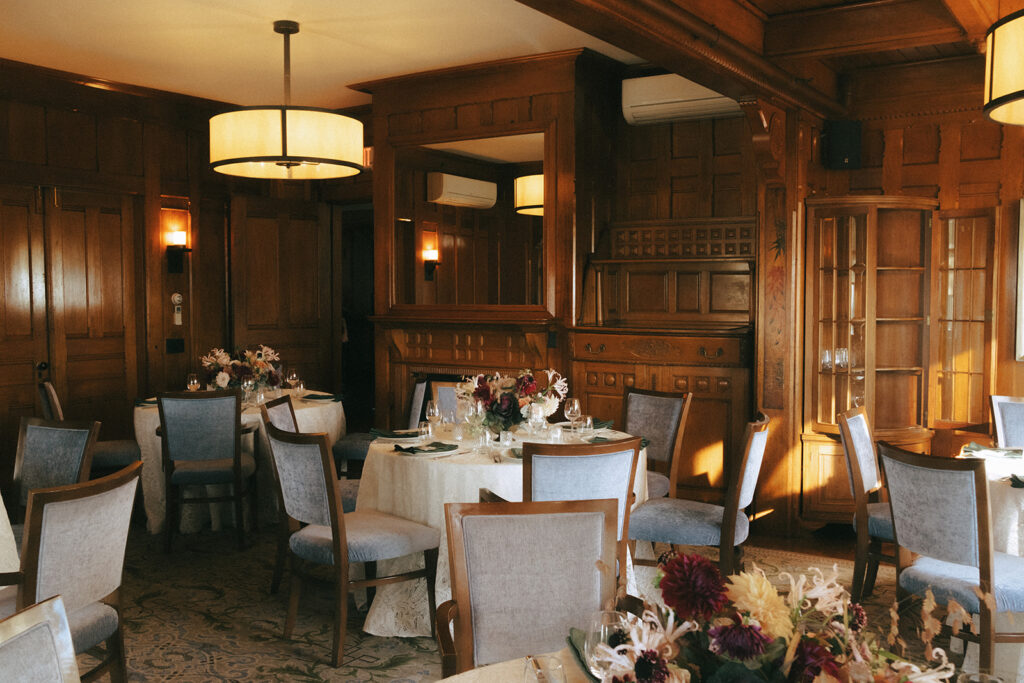 Wide shot of the Ocean Room at Castle Hill Inn. Blue and wood chairs and tables with lace linens and floral arrangements fill the space. Photo by Rhode Tripper Photography