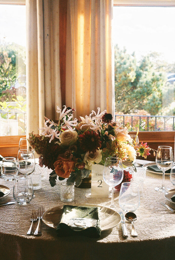 Floral centerpiece full of blush and burgundy fall tones sits atop a fully set table with lace linens. Setting is the Ocean Room at Castle Hill Inn in Newport, RI. Photo by Rhode Tripper Photography