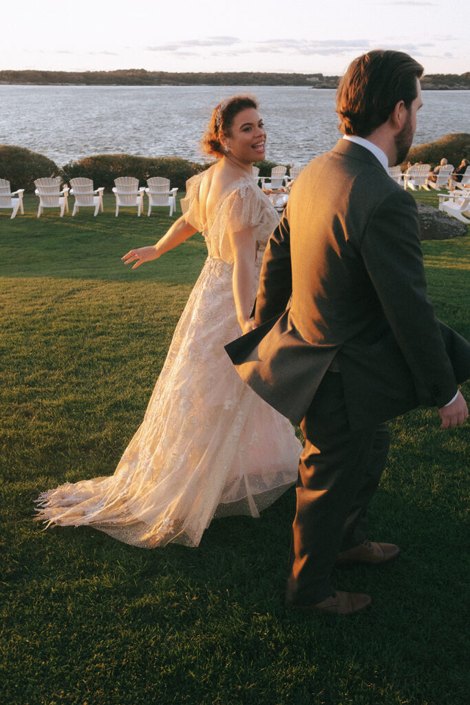 Couple smiles and holds hands as they walk the Castle Hill lawn on their wedding day. Photo by Rhode Tripper Photography