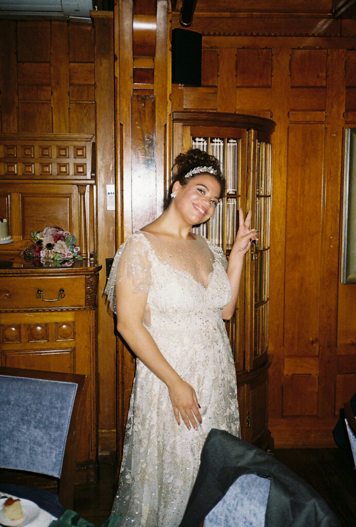 Bride holds up a peace sign during her wedding reception at Castle Hill. Photo by Rhode Tripper Photography