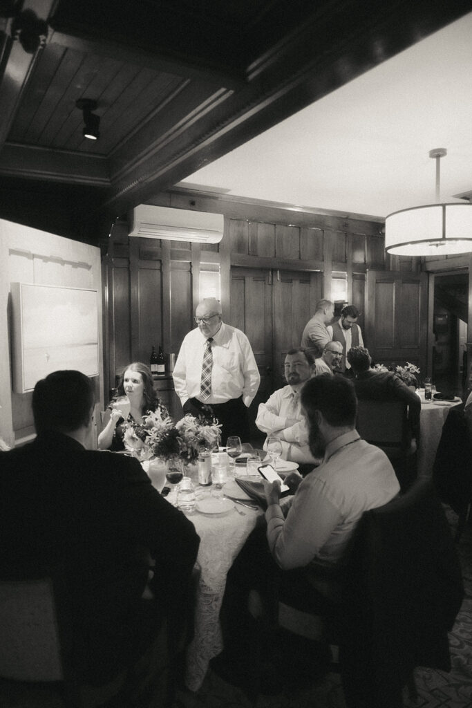 Black and white photo of guests mingling in the Ocean Room for a wedding reception at Castle Hill Inn. Photo by Rhode Tripper Photography