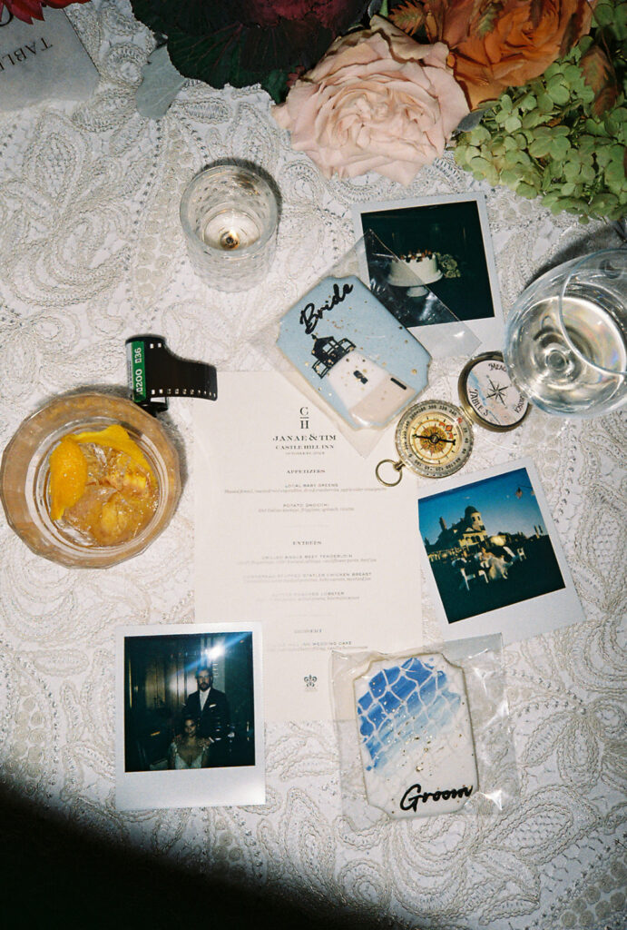 Late night flat lay on film. Half consumed drinks, the wedding menu, rolls of film, Polaroids, florals and candles fill the frame as a showcase of the evening details from this Castle Hill wedding. Photo by Rhode Tripper Photography