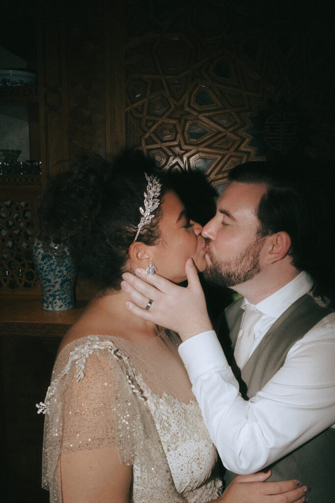 Close up with direct of the bride and groom. Groom holds the bride's face in his hand and gives her a big kiss. Photo by Rhode Tripper Photography