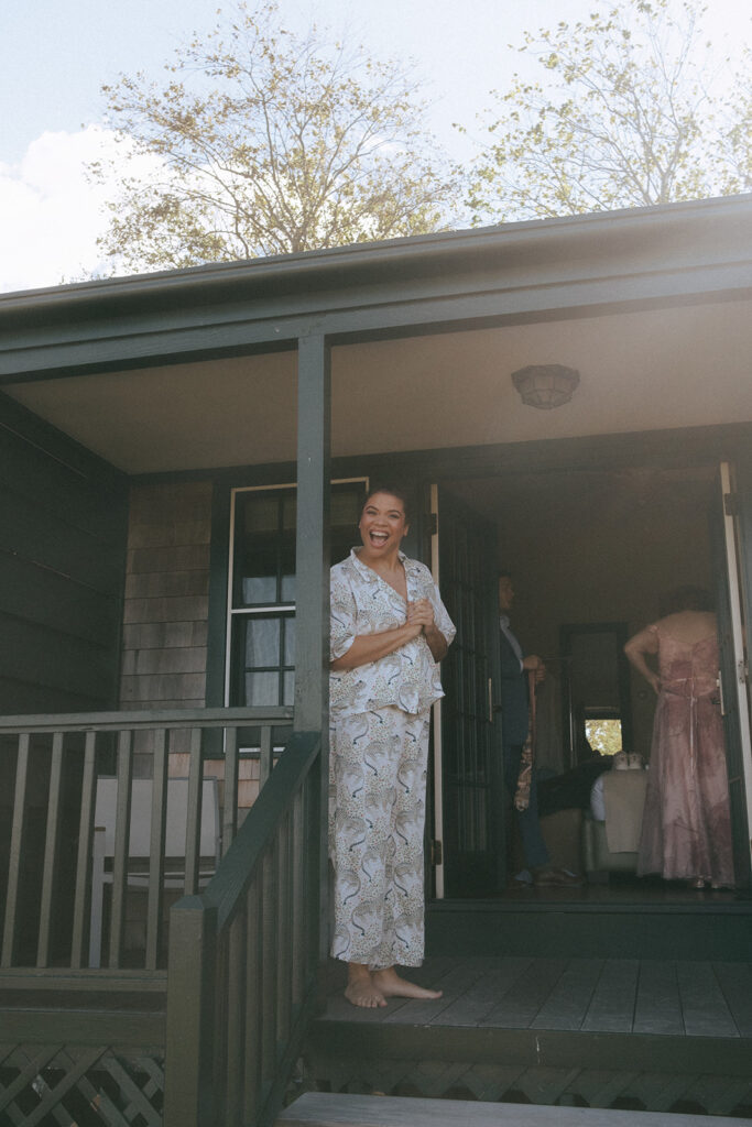 Bride in her pajamas smiles and greets us as she waits on the porch of her Harbor House guest room at Castle Hill Inn. Photo by Rhode Tripper Photography