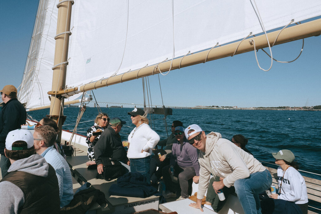 Guests look out towards the bay while sitting and standing aboard the ship. Photo by Rhode Tripper Photography