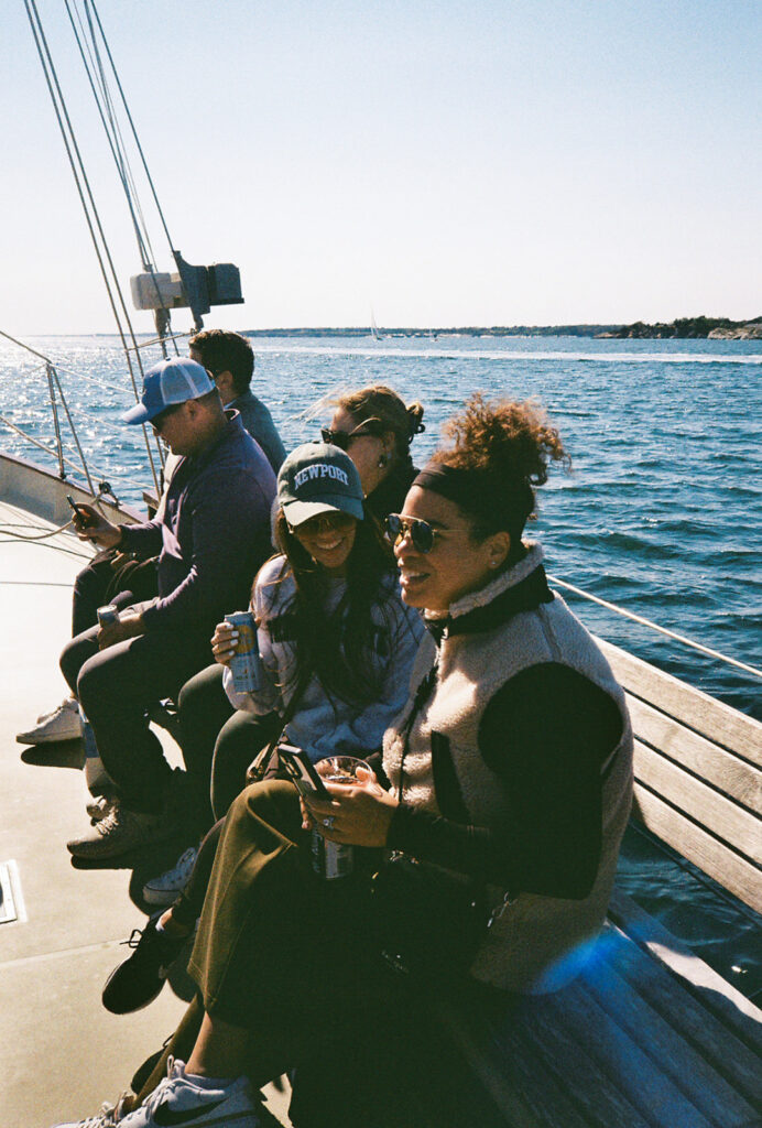 Bride sits amongst guests aboard the Schooner Aquidneck while sailing in Newport. Photo by Rhode Tripper Photography