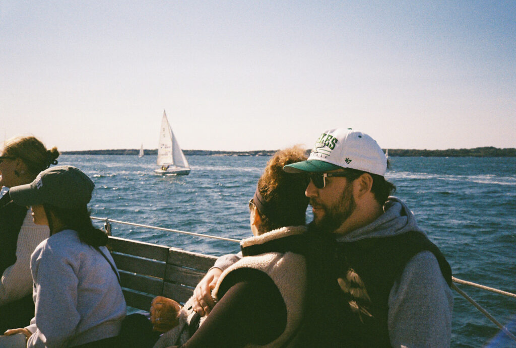 Photo on film. Couple looks out towards a sailboat on the bay in Newport, RI. Photo by Rhode Tripper Photography