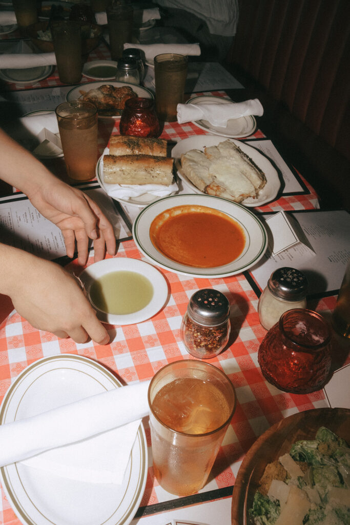 Servers placed olive oil and sauce on a red checkered tablecloth as they prepare to greet guests. Wedding reception at Tony and Elaine's Boston.