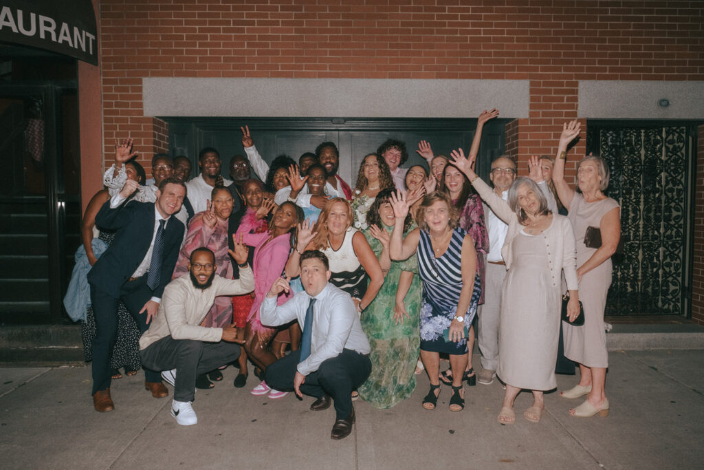 20 guests stand outside Tony and Elaine's Boston for a group photo with the bride and groom.