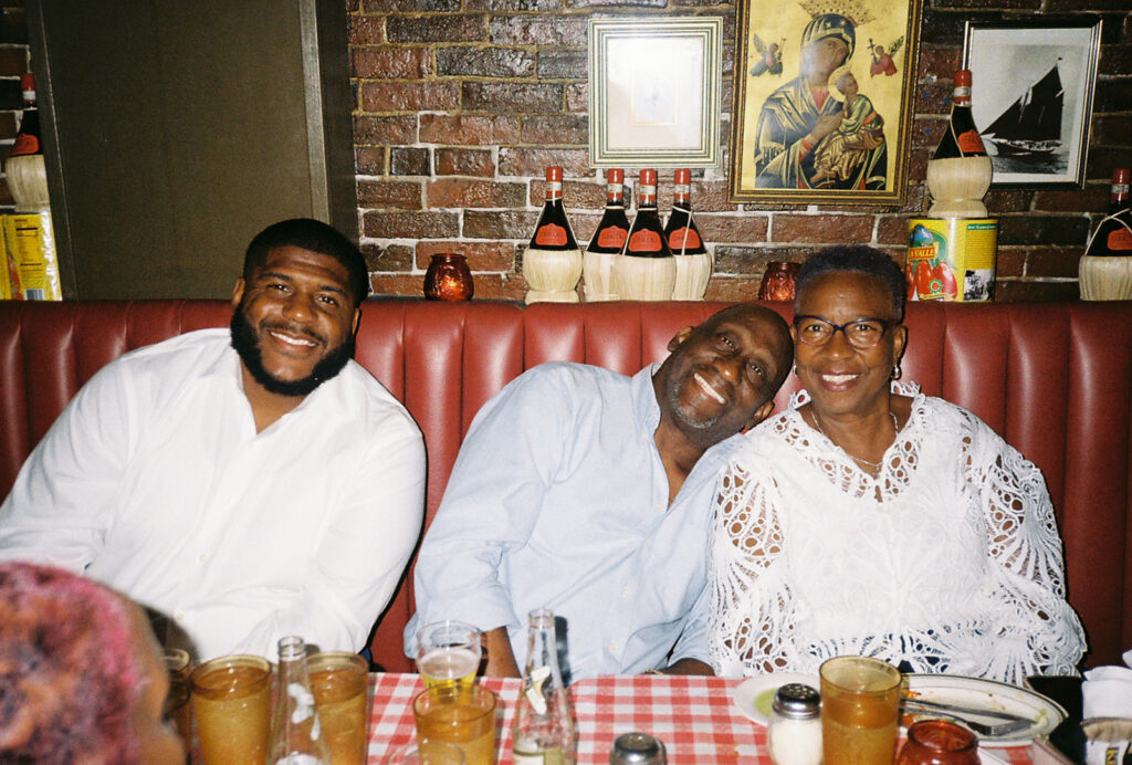 Groom's family smiles and snuggles in the red leather booths at Tony and Elaine's. Wedding guests at reception.