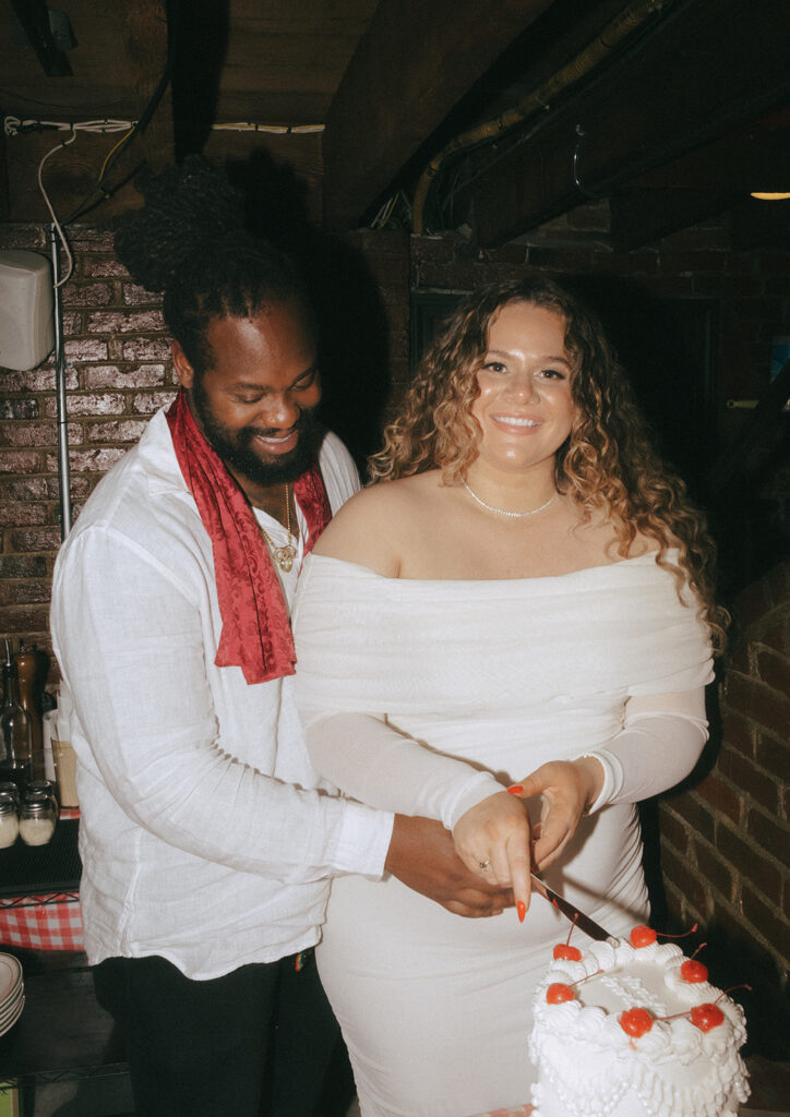 Couple cutting vintage inspired heart shaped cake at their Tony and Elaine's Boston micro wedding reception.