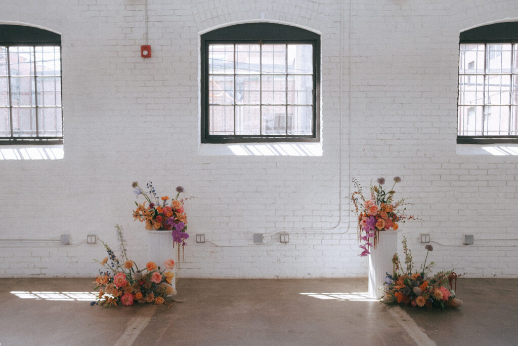 Colorful spring floral columns for ceremony altar at boutique hotel wedding. Photo by Rhode Tripper Photography