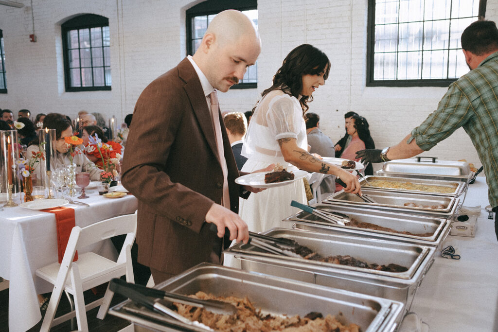 Bride and groom enjoying food from their Durk's BBQ wedding buffet at boutique hotel reception in ProvidencePhoto by Rhode Tripper Photography