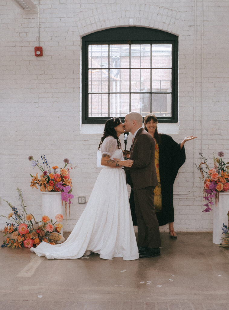 Newlyweds sharing first kiss at spring wedding ceremony in Providence. Photo by Rhode Tripper Photography