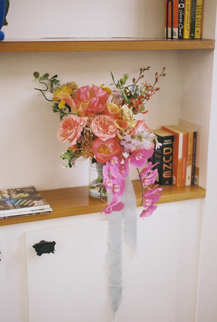 Colorful bouquet resting on bookshelf at industrial chic hotel. Photo by Rhode Tripper Photography