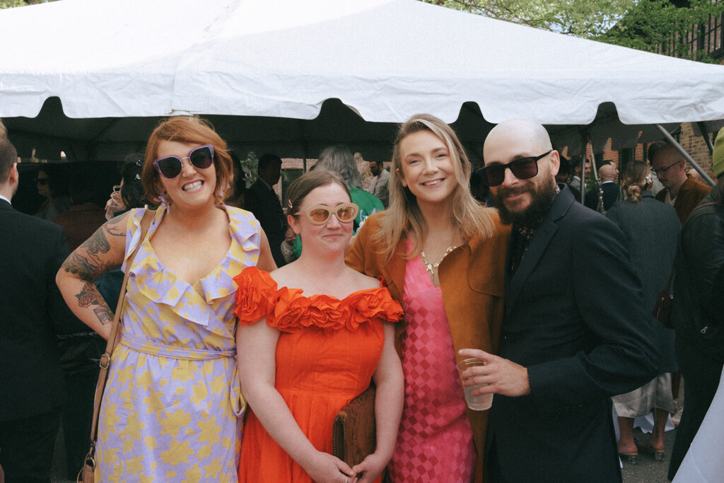 Wedding guests enjoying cocktail hour under tent at boutique hotel venue. Photo by Rhode Tripper Photography