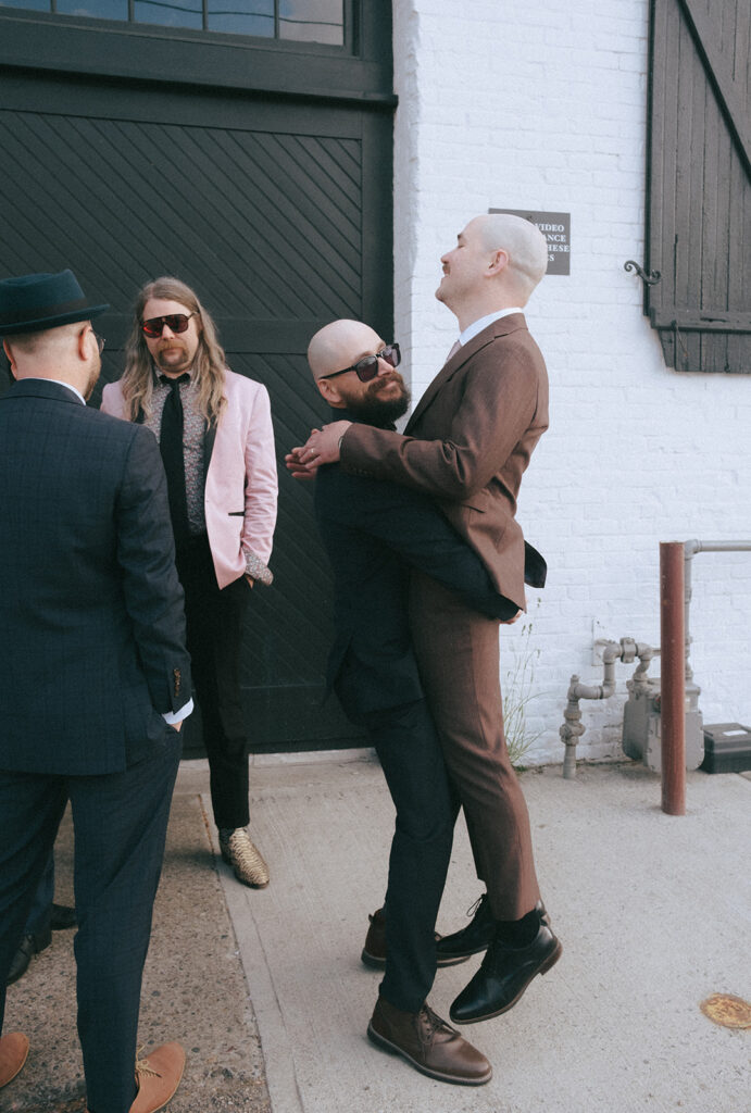 Candid moment of groom's friend lifting groom into the air at his spring wedding. Photo by Rhode Tripper Photography