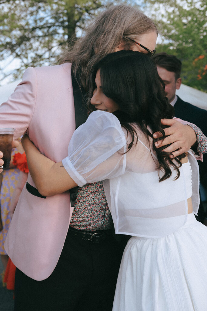 Candid moment of bride embracing friend during outdoor cocktail hour in Providence. Photo by Rhode Tripper Photography