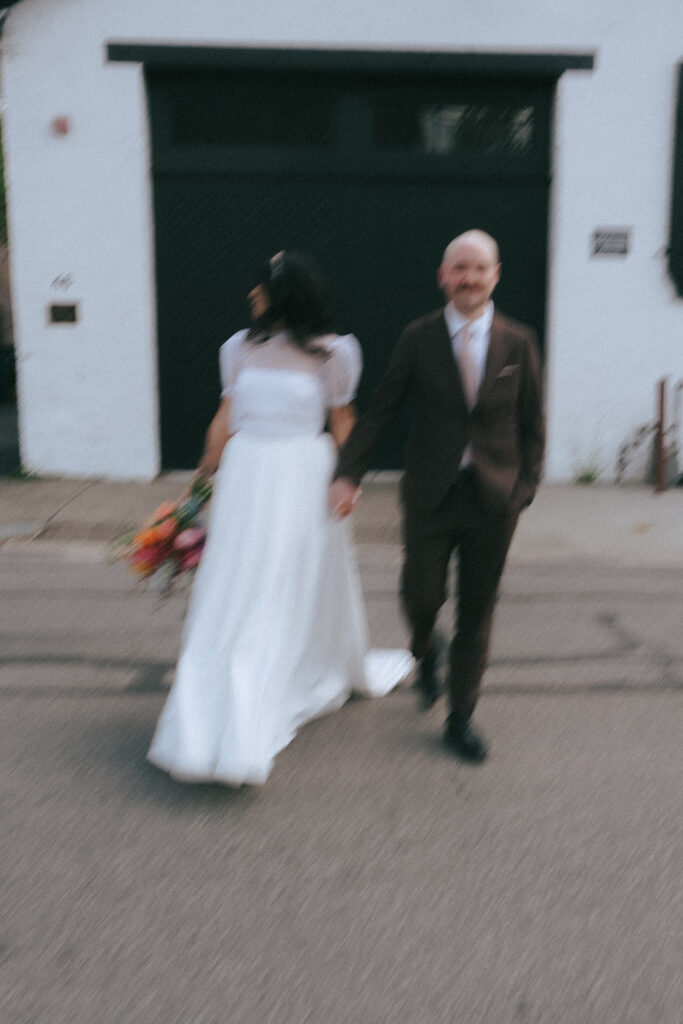 Newlyweds walking hand in hand on Providence street near boutique hotel venue. Photo by Rhode Tripper Photography